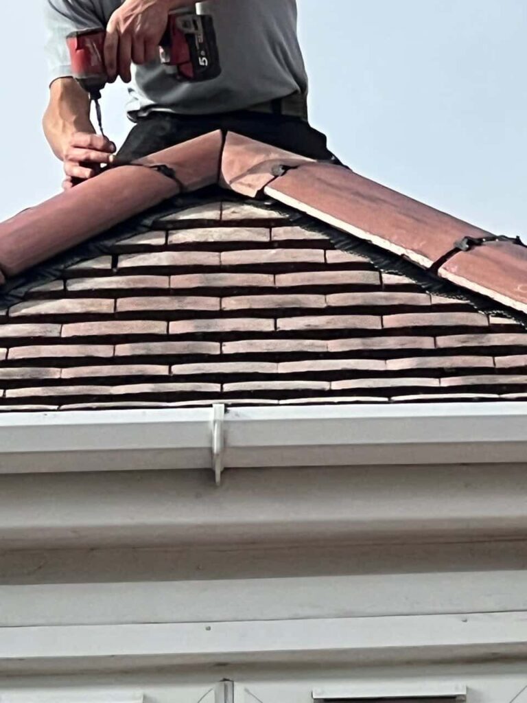 This is a photo of one of the operatives of Gamston Roofing Repairs installing new ridge tiles